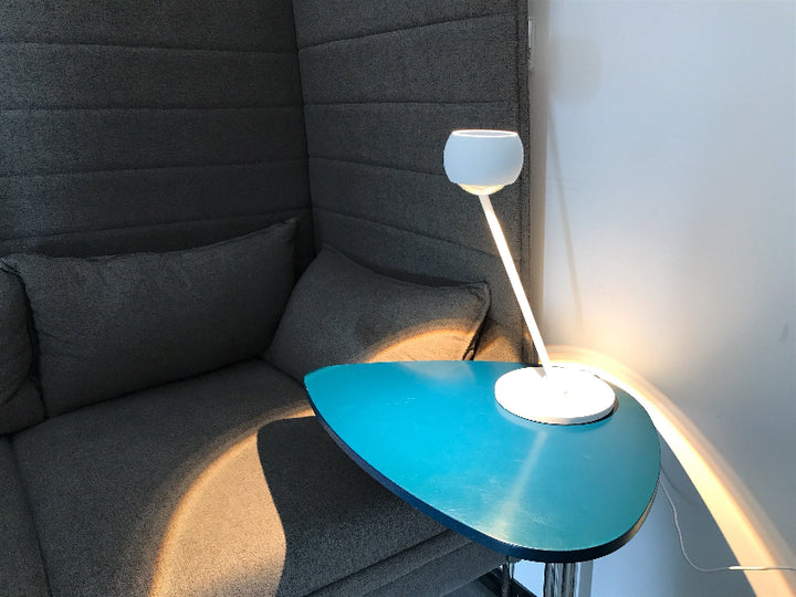 Helles Licht mit der Tischleuchte Lens auf einem Beistelltisch zum punktgenauen Ausleuchten von Schriftgut.